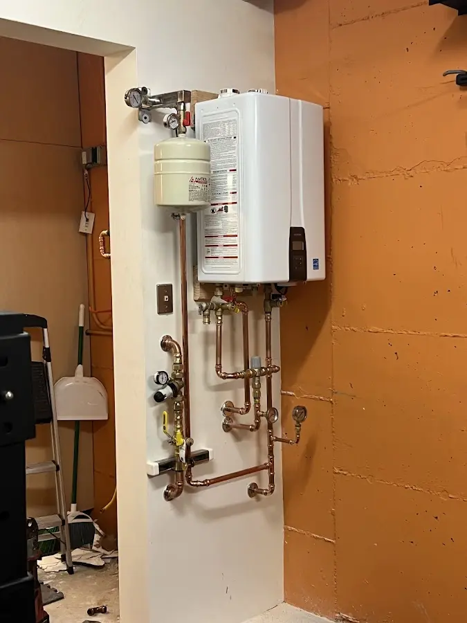 Plumbing technician inspecting water heater connections in West Manheim
